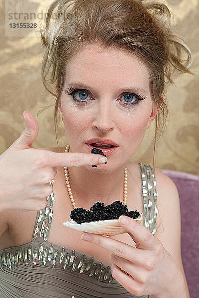 Frau im Abendkleid isst Kaviar