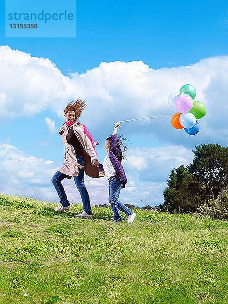 Mutter und Tochter mit Luftballons im Wind