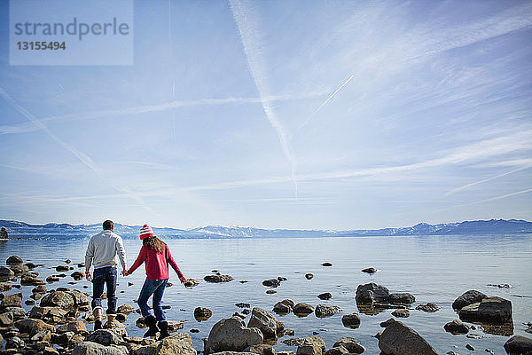 Paar geht auf Felsen in der Nähe des Sees