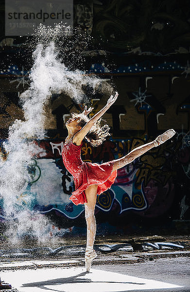 Ballett tanzendes Mädchen  das weißes Pulver vor einem Graffiti verstreut