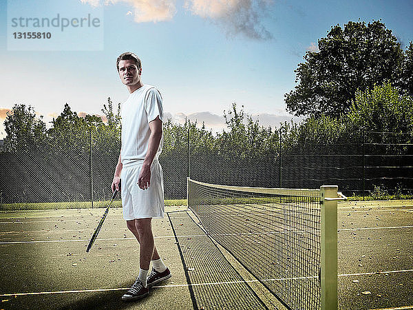 Mann steht auf Tennisplatz