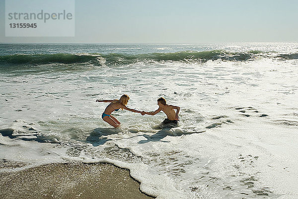 Pärchen hilft sich gegenseitig beim Surfen