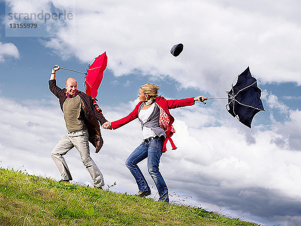 Paar mit Regenschirmen im Wind