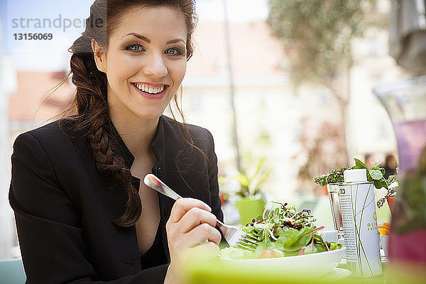 Junge erwachsene Frau isst Salat  draußen
