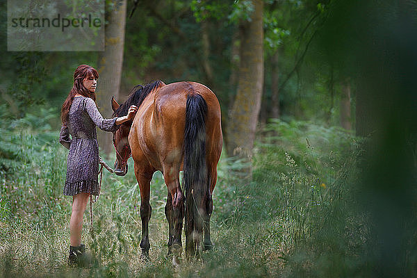 Frau geht mit Pferd im Wald spazieren