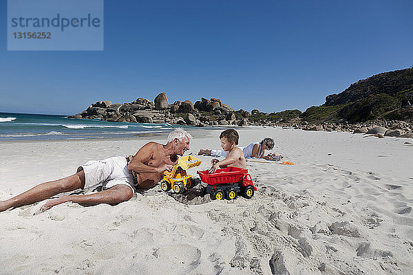 Mann spielt mit Enkel am Strand