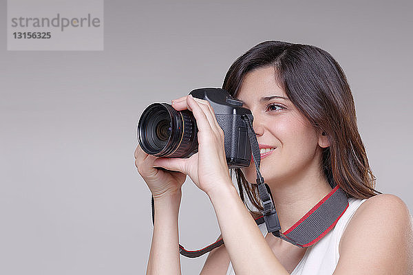 Junge Frau beim Fotografieren mit digitaler Spiegelreflexkamera
