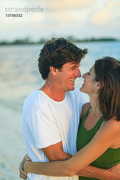 Lächelndes  sich umarmendes Paar am Strand