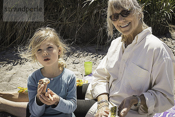 Großmutter und Enkelin am Strand mit Picknick