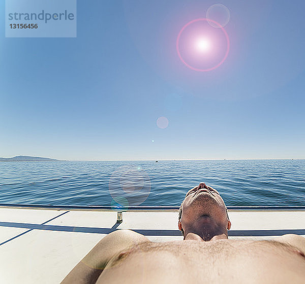 Mann auf Segelboot beim Sonnenbaden