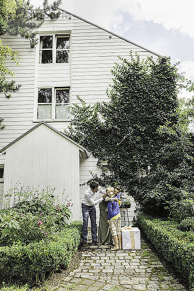 Älteres Paar begrüßt Enkel im Garten