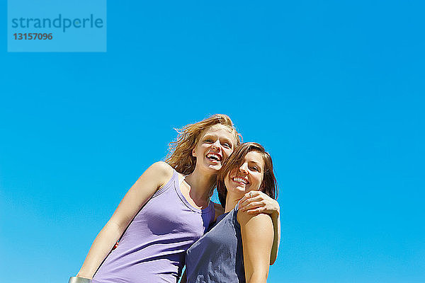 Porträt von zwei Mädchen vor blauem Himmel