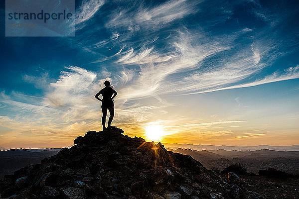 Silhouette einer mittleren erwachsenen Frau  die bei Sonnenuntergang auf einem Berggipfel steht  Rückansicht  Ryan Mountain Hiking Trail  Joshua Tree National Park  Kalifornien  USA