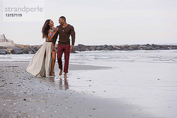 Ehepaar geht lachend am Strand entlang