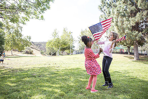 Mädchen mit amerikanischen Flaggen spielen im Park