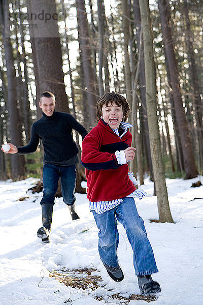 Vater und Sohn werfen mit Schneebällen