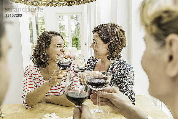 Vier erwachsene Freunde stoßen beim Abendessen mit Rotwein an