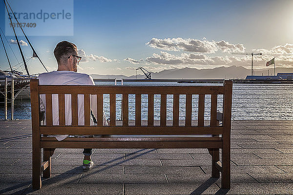 Junger Mann entspannt sich auf einer Bank am Hafen  Cagliari  Sardinien  Italien