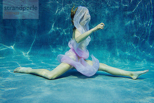 In Stoff gehüllte Frau schwimmt halbnackt unter Wasser