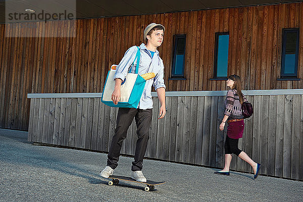 Junger Mann auf Skateboard mit Einkäufen