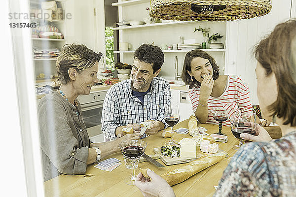 Erwachsene Freunde trinken Rotwein und spielen Karten am Esstisch