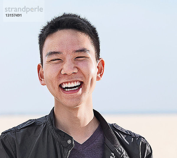 Porträt eines lächelnden jungen Mannes am Strand
