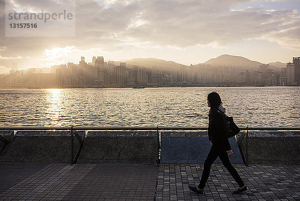 Seitenansicht einer jungen Frau  die am Wasser entlang geht  Hongkong  China