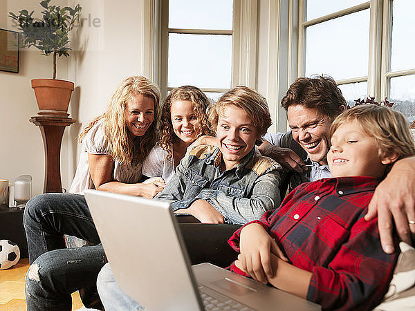 Familie schaut gemeinsam auf dem Sofa Laptop