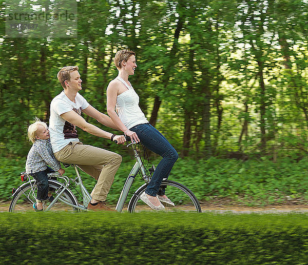 Familie mit einem Kind fährt gemeinsam auf dem Fahrrad