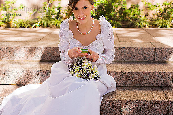 Braut mit Mobiltelefon vor der Hochzeit