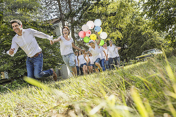 Eine Gruppe von Menschen läuft durch den Wald  ein Junge hält ein Bündel Luftballons