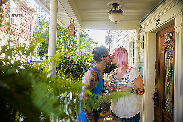 Flippiges Paar küsst sich auf Veranda
