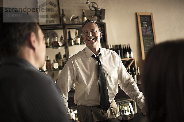 Barkeeper plaudert mit Kunden in einer Weinbar