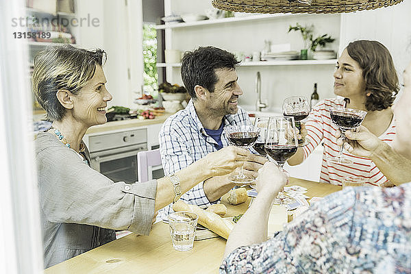 Erwachsene Freunde  die am Esstisch mit Wein anstoßen