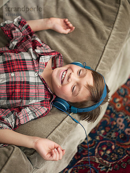 Junge entspannt sich auf dem Sofa und trägt Kopfhörer