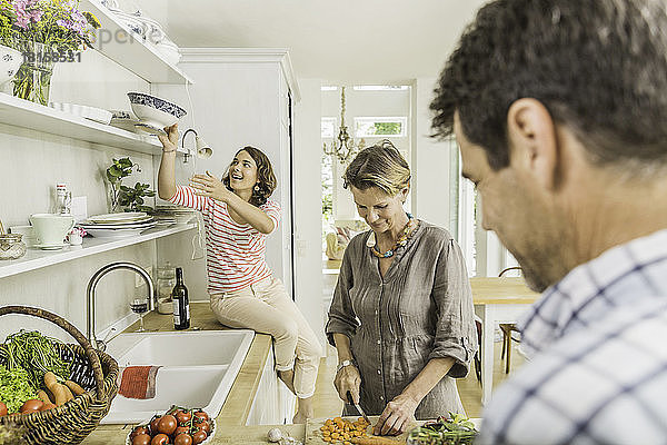 Drei Erwachsene bereiten in der Küche frisches Gemüse zu