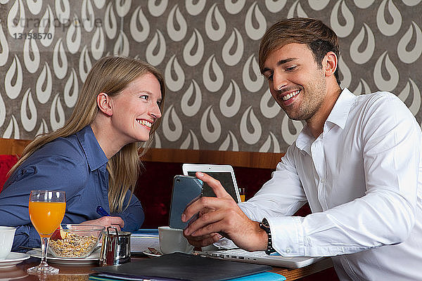 Lächelndes Paar benutzt Handy im Café