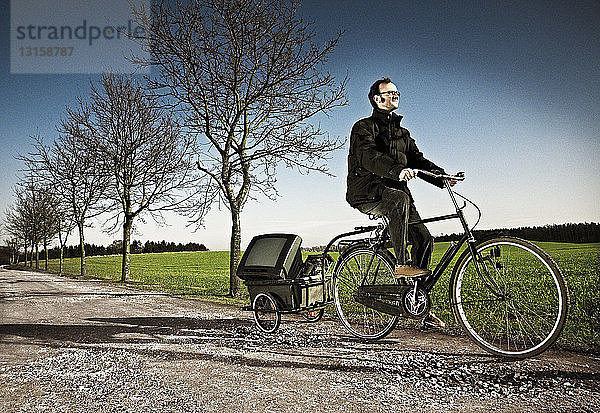 Mann fährt Fahrrad mit Kutsche auf Landstraße  Ringsted  Dänemark