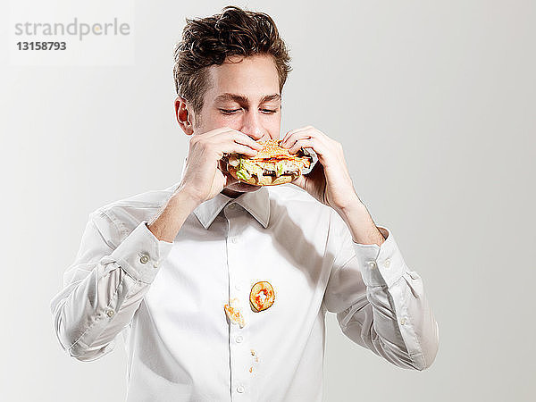 Junger Mann isst unordentliches Sandwich  Studioaufnahme