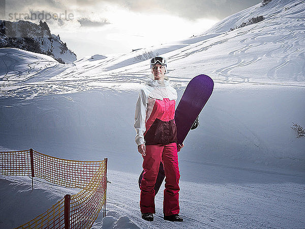 Frau mit Snowboard auf verschneiter Piste