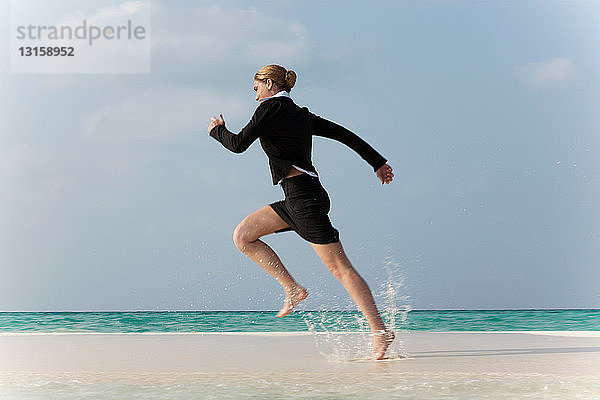 Geschäftsfrau läuft am tropischen Strand