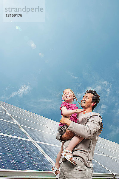 Mann und Tochter vor einem Sonnenkollektor