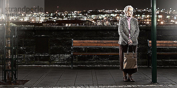 Ältere Frau wartet nachts auf den Bus