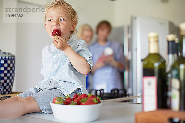 Junge isst Erdbeeren auf der Theke