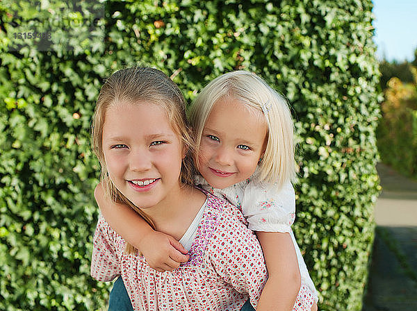 Mädchen  von Schwester auf dem Rücken getragen  lächelnd  Porträt