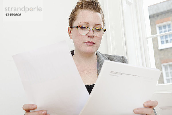Geschäftsfrau liest Papiere am Schreibtisch