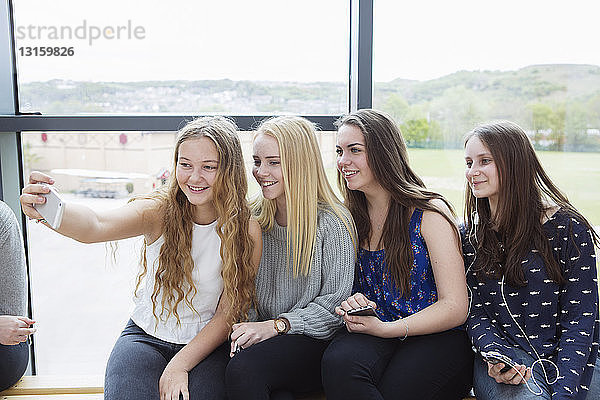 Teenager-Mädchen nehmen Selfie mit Smartphone auf Bank