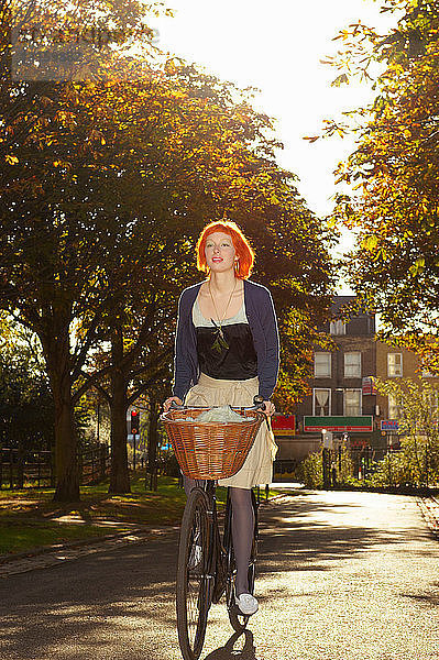 Junge rothaarige Frau beim Radfahren im Park