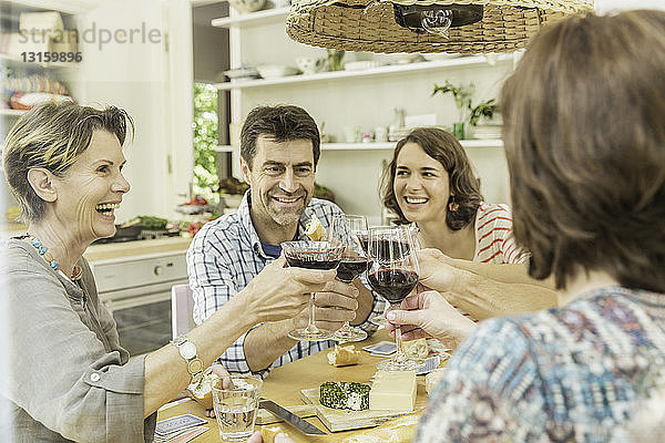 Erwachsene Freunde  die am Esstisch mit Rotwein anstoßen