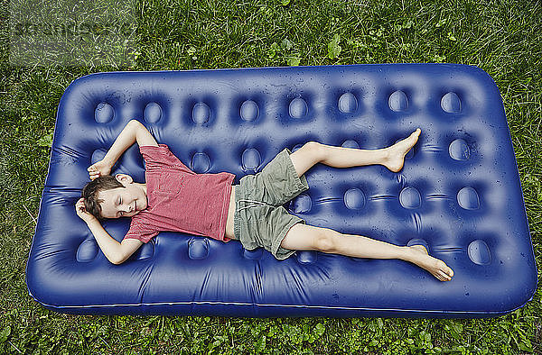 Draufsicht auf einen Jungen  der auf einer aufblasbaren Matratze liegt